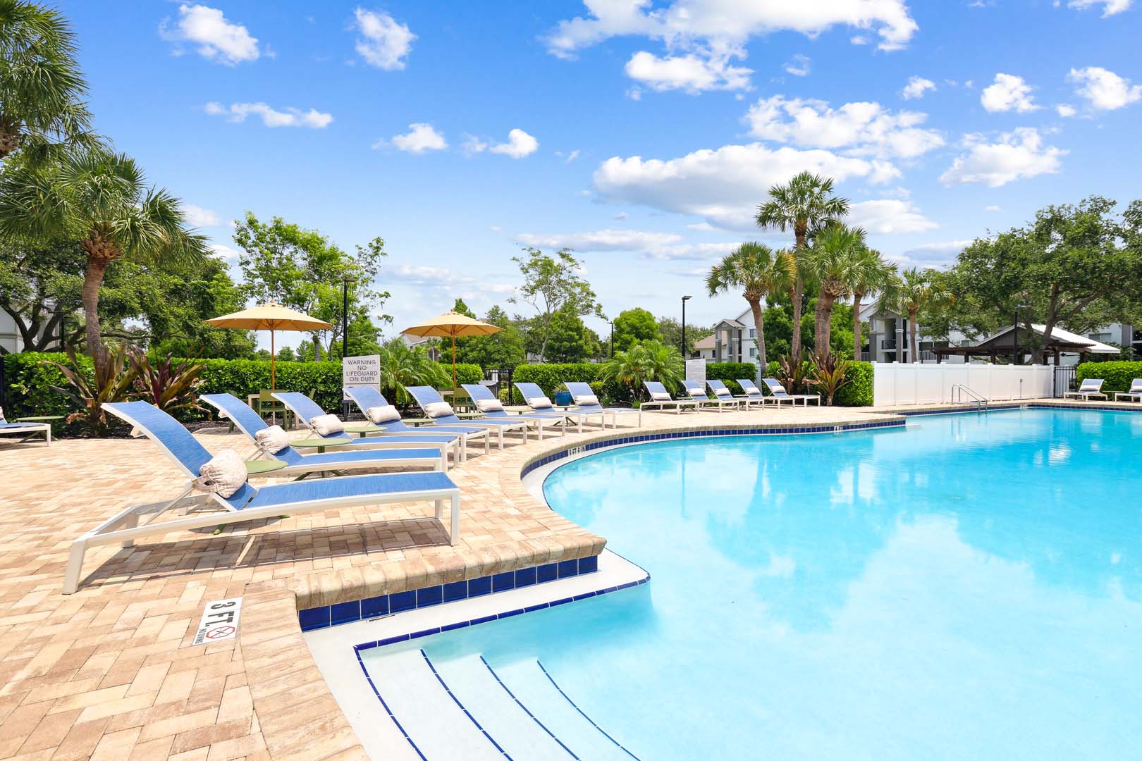 wide view of pool with large tanning deck and lounge chairs